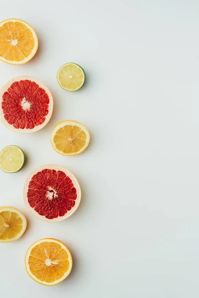 Vista superior de rodajas de pomelo, limón, lima y naranja, en gris con espacio para copiar - foto de stock