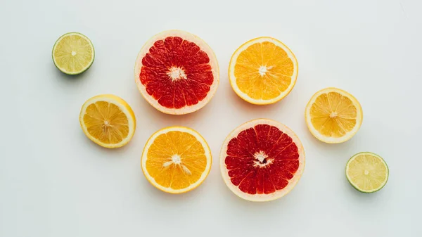 Vista dall'alto di fette di pompelmo fresco, limone, lime e arancia, su grigio — Foto stock