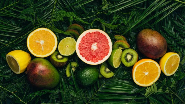 Vue de dessus des fruits tropicaux frais sur les feuilles de palmier — Photo de stock