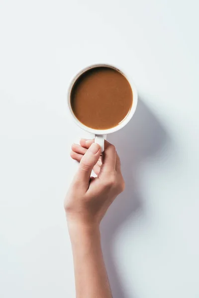 Tiro cortado de mulher segurando xícara de café na superfície branca — Fotografia de Stock