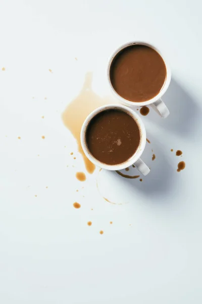 Vista superior de xícaras de café em pé bagunçado na superfície branca — Fotografia de Stock