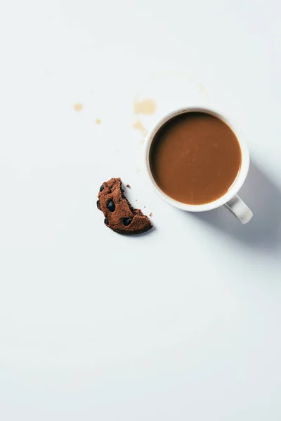 Top view of cup of coffee with bitten chocolate chip cookie on white surface — Stock Photo
