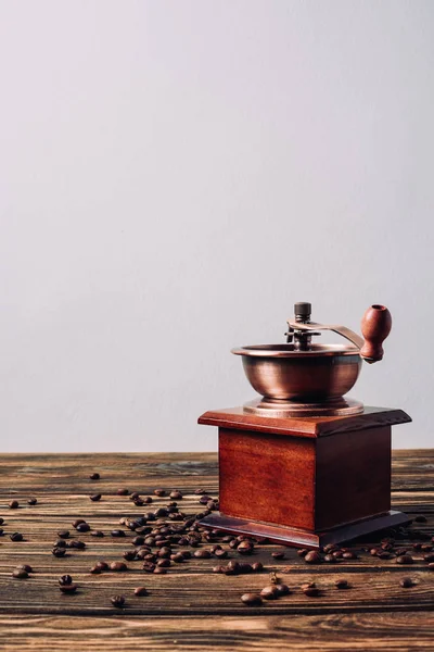Старинная кофемолка с кофейными зернами на деревенском деревянном столе — стоковое фото
