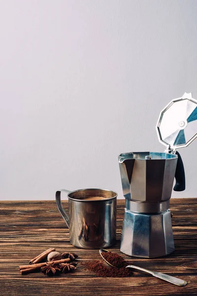Металлическая кружка кофе с кофейником и специями на деревенском деревянном столе — стоковое фото