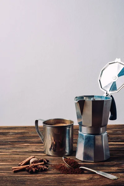 Metal mug of coffee with mocha pot and spices on rustic wooden table — Stock Photo