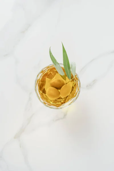 Ansicht von Olivenzweig mit Oliven im Glas auf Marmortisch — Stockfoto