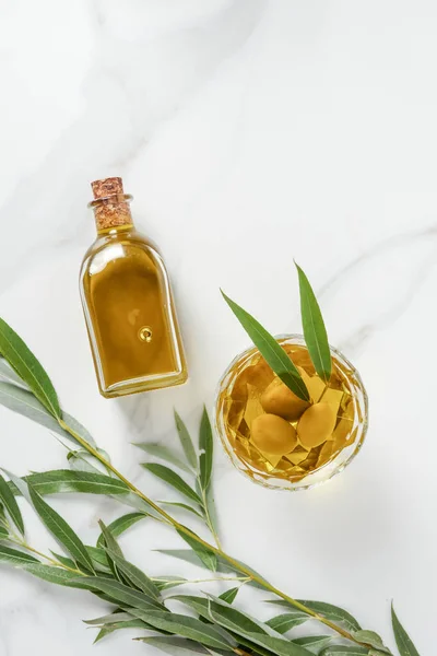 Elevated view of bottle and glass with olive oil on marble tabletop — Stock Photo