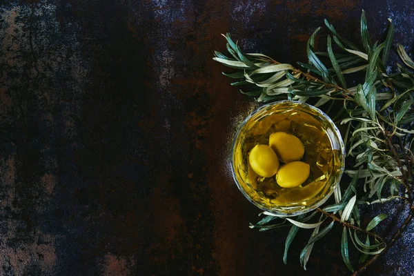 Vista dall'alto di vetro di olio d'oliva e ramoscelli sul tavolo di marmo — Foto stock