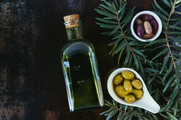 Top view of bottle of olive oil and olives in bowls on shabby surface — Stock Photo