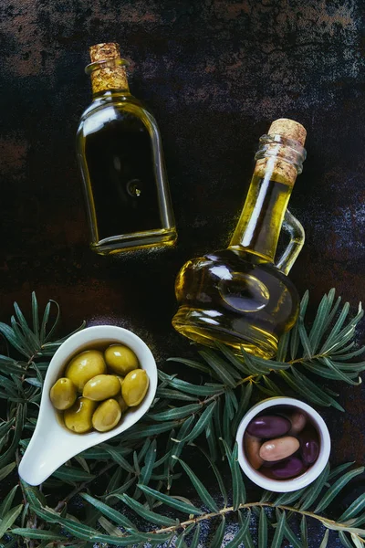 Vista dall'alto di due bottiglie di olio d'oliva fatto in casa e olive su superficie squallida — Foto stock