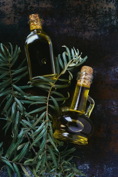 Vue de dessus de deux bouteilles d'huile d'olive et de brindilles sur une surface minable — Photo de stock