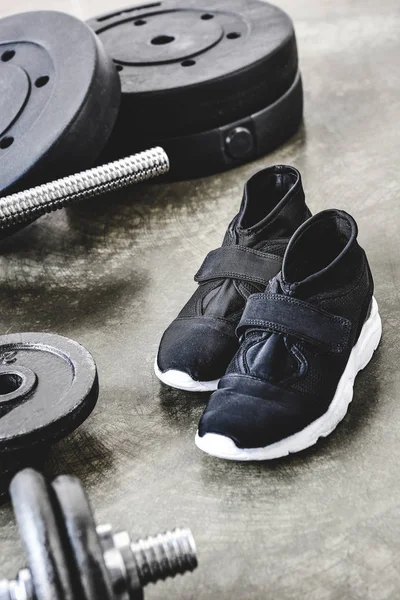 Close-up shot of sneakers and weight plates on concrete surface — Stock Photo