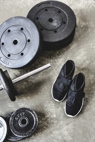 Top view of barbell with weight plates and sneakers on concrete floor — Stock Photo