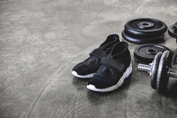 Close-up shot of weight plates and sneakers on concrete floor — Stock Photo