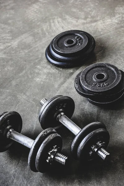 Close-up shot of dumbbells with weight plates on concrete surface — Stock Photo