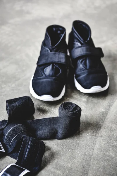 Close-up shot of sneakers and wrist wraps on concrete floor — Stock Photo
