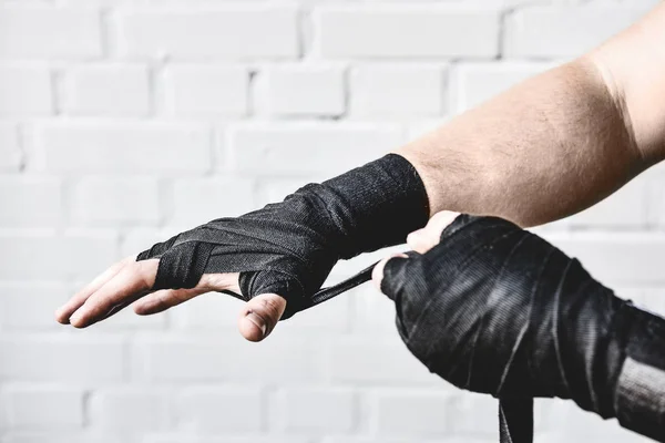 Plan recadré de haltérophilie enveloppant les mains avant l'entraînement devant un mur de briques blanches — Photo de stock