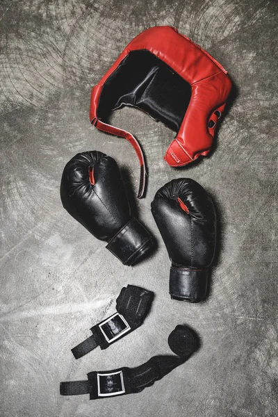 Vista superior de luvas de boxe e capacete com envoltórios de pulso deitado na superfície de concreto — Fotografia de Stock
