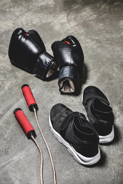 Sneakers with jumping rope and boxing gloves on concrete surface — Stock Photo
