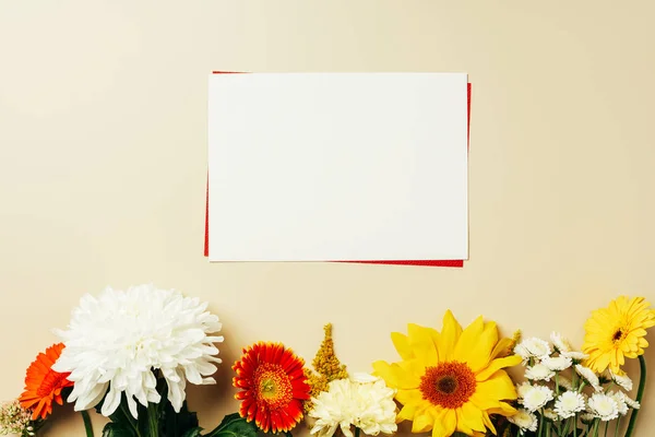 Flat lay with arrangement of red and white blank cards and various flowers on beige backdrop — Stock Photo