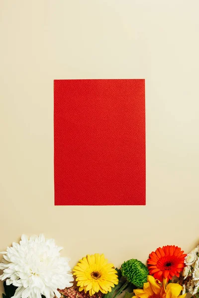 Vista superior de la bandera roja vacía y flores arregladas sobre fondo beige - foto de stock