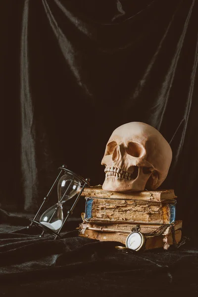 Halloween-Totenkopf auf antiken Büchern mit Sanduhr auf schwarzem Tuch — Stockfoto