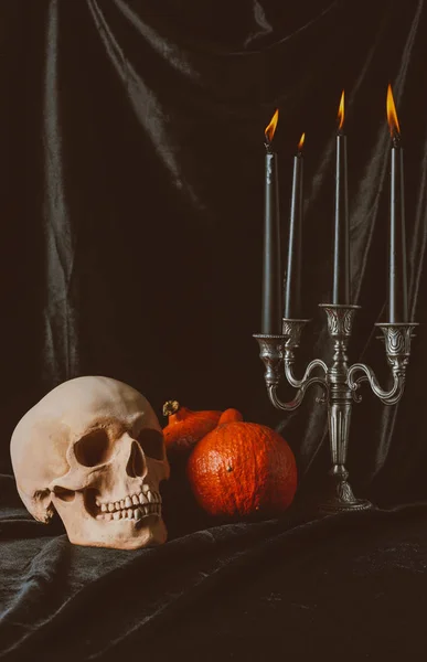 Calavera, calabazas y candelabro con velas sobre tela negra - foto de stock