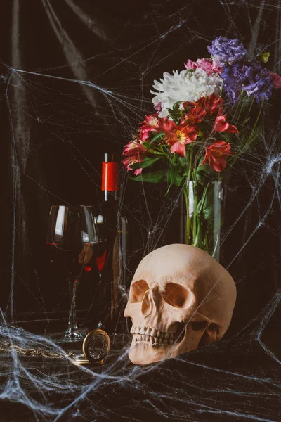 Crânio, vinho tinto, relógio vintage e flores em pano preto com teia de aranha — Fotografia de Stock