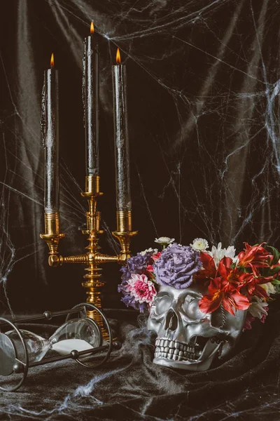 Clessidra, teschio in argento con fiori e candelabro con candele su tela nera con ragnatela, decorazioni per Halloween — Foto stock