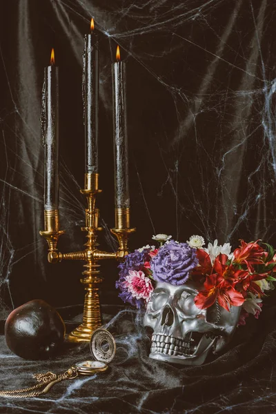 Silver skull, candles and halloween decorations on black cloth with spider web — Stock Photo