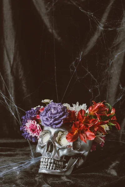 Cráneo de plata con flores en tela negra con tela de araña para halloween - foto de stock