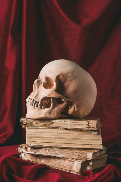 Halloween-Totenkopf auf alten Büchern auf rotem Tuch, Stilleben mit Hexerei — Stockfoto