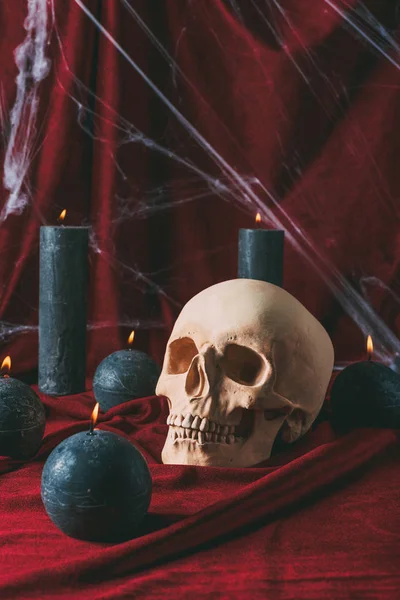 Skull and black candles on red cloth with spider web for halloween — Stock Photo