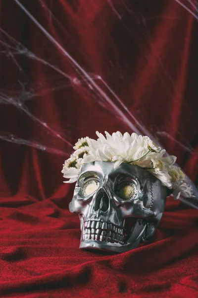 Halloween silver skull with flowers on red cloth with spider web — Stock Photo