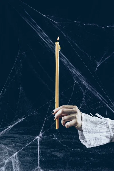 Partial view of gothic woman holding candle in darkness with spider web — Stock Photo