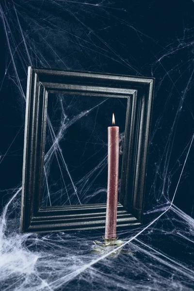 Black frame and red candle in spider web, creepy halloween decor — Stock Photo