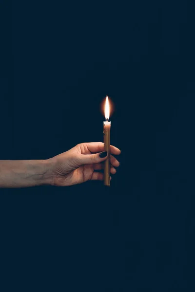 Vista parziale della ragazza che tiene candela fiammeggiante isolata sul nero — Foto stock