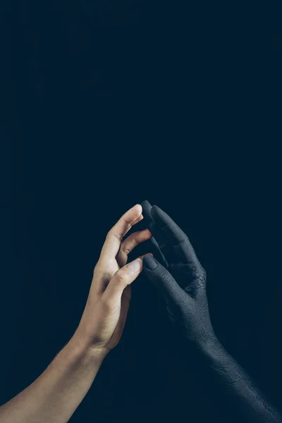 Vista cortada de mulher tocando com mão demônio preto isolado em preto — Fotografia de Stock