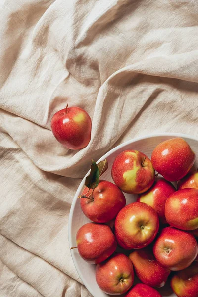 Pommes rouges dans un bol blanc sur toile de sac — Photo de stock