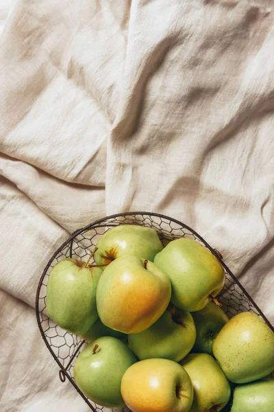 Вид сверху на зеленые яблоки в металлической корзине на мешковатой ткани — стоковое фото