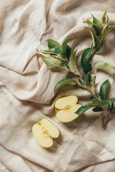 Two halves apple with apple tree leaves on sacking cloth — Stock Photo