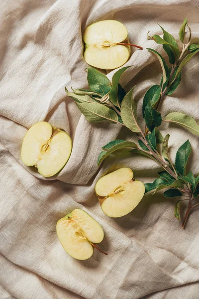 Top view of apple halves with apple tree leaves on sacking cloth — Stock Photo