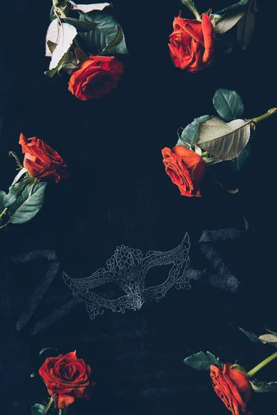 Von oben mit Spitzenmaske und schönen roten Rosen auf schwarz — Stockfoto