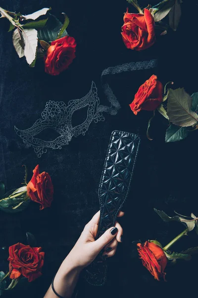 Cropped shot of woman holding black leather spanking paddle — Stock Photo