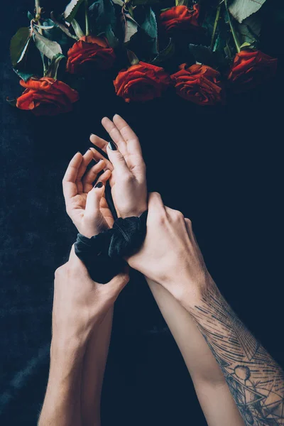 Cropped shot of man tying female hands with black ribbon — Stock Photo