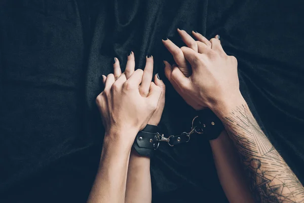 Обрізаний знімок пари, що тримає руки в передпокої, жінка в шкіряних наручниках — стокове фото