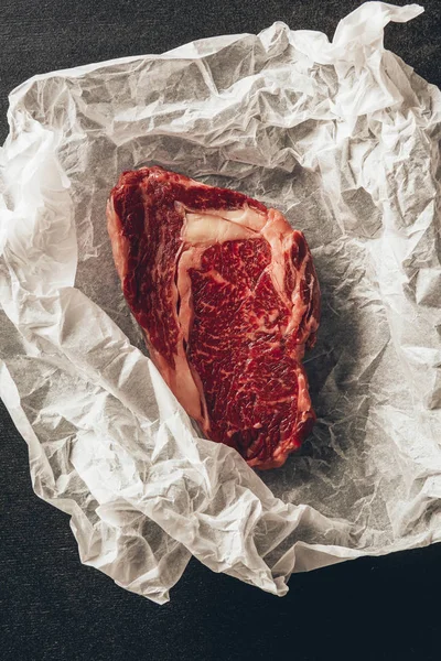 Elevated view of raw meat steak on baking paper in kitchen — Stock Photo