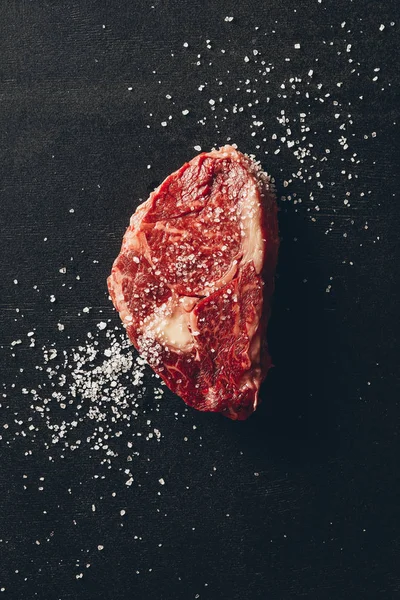 Вид сырого мяса стейк и соль на поверхность на кухне — стоковое фото