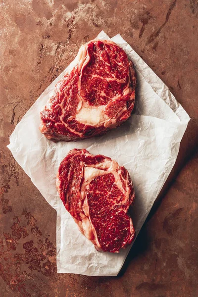 Vue de dessus de deux steaks crus sur papier cuisson dans la cuisine — Photo de stock
