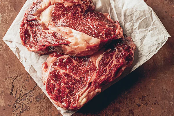 Elevated view of two uncooked steaks on baking paper in kitchen — Stock Photo